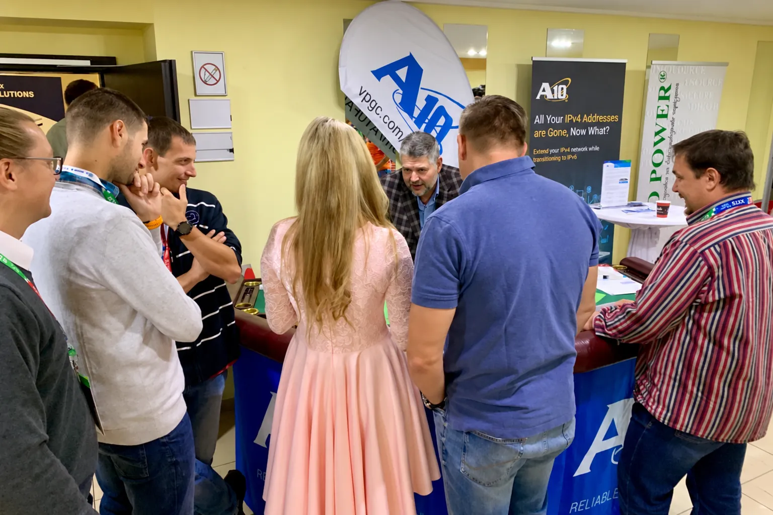 Skupina návštěvníků veletrhu sleduje interaktivní moment u firemního stánku s technologickými bannery